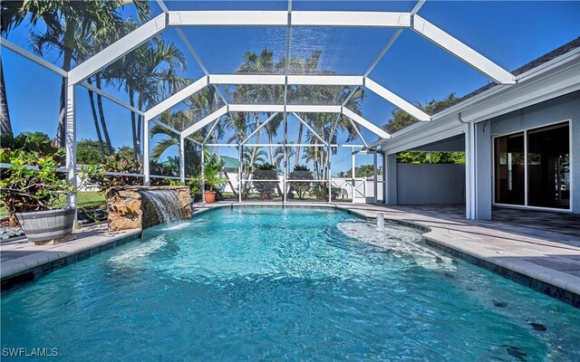 view of pool featuring pool water feature, glass enclosure, and a patio area