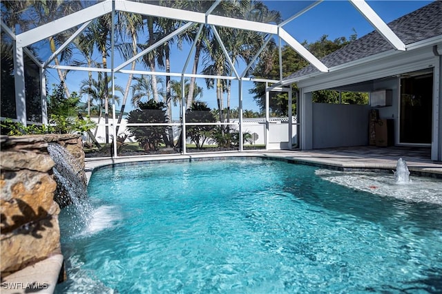 view of swimming pool with pool water feature, glass enclosure, and a patio