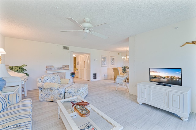 living room with ceiling fan with notable chandelier, a textured ceiling, and light wood-type flooring