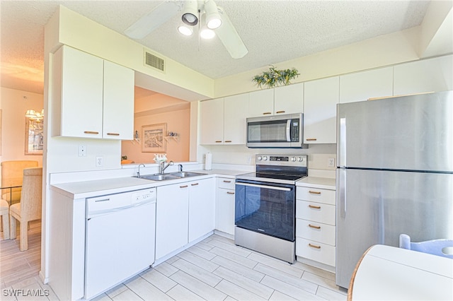 kitchen featuring white cabinetry, sink, a textured ceiling, appliances with stainless steel finishes, and light wood-type flooring