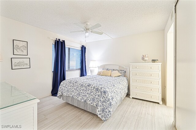 bedroom featuring light wood-type flooring, a textured ceiling, and ceiling fan