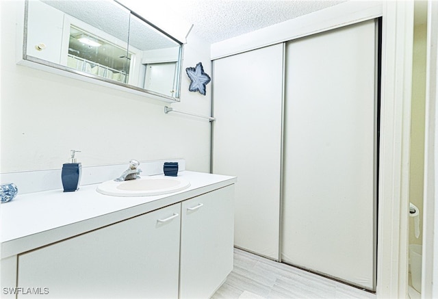 bathroom with hardwood / wood-style floors, vanity, a textured ceiling, and walk in shower