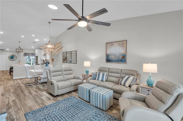 living room featuring light hardwood / wood-style floors, lofted ceiling, and ceiling fan with notable chandelier