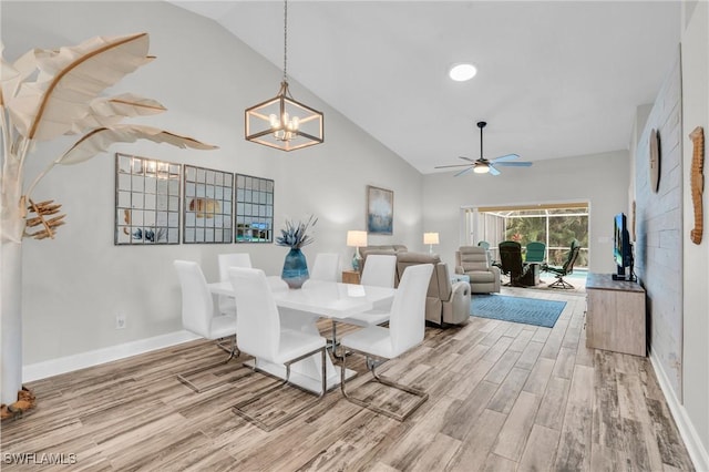 dining room with vaulted ceiling, ceiling fan with notable chandelier, and wood-type flooring