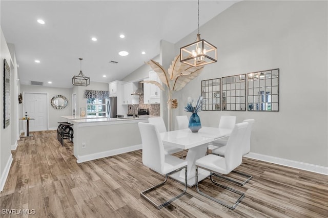 dining area featuring sink, light hardwood / wood-style flooring, and lofted ceiling