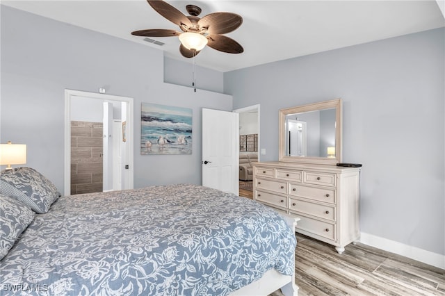 bedroom with ensuite bath, ceiling fan, and light hardwood / wood-style flooring