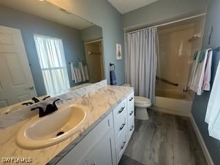 full bathroom with toilet, shower / bath combination with curtain, hardwood / wood-style flooring, and vanity