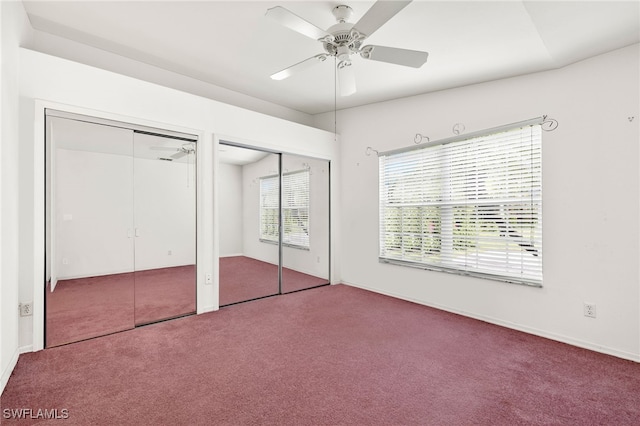 unfurnished bedroom featuring carpet, ceiling fan, and two closets