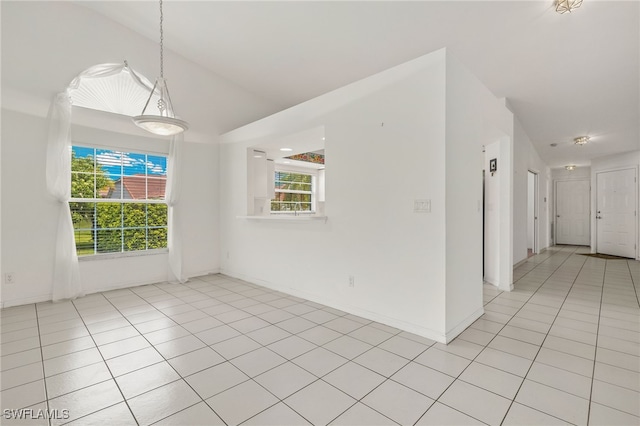 tiled spare room featuring lofted ceiling