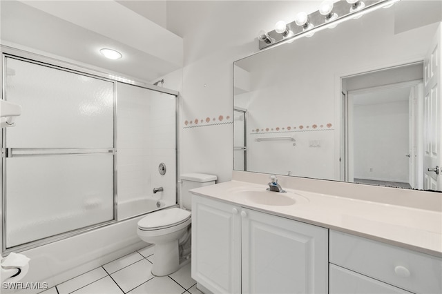 full bathroom with tile patterned floors, vanity, bath / shower combo with glass door, and toilet