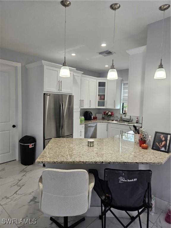 kitchen with a peninsula, white cabinetry, glass insert cabinets, and stainless steel appliances