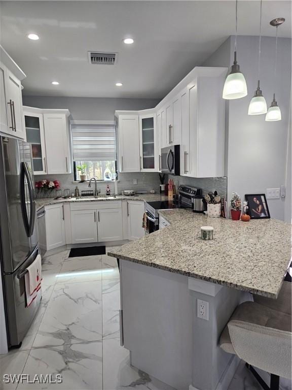 kitchen with a breakfast bar, visible vents, stainless steel appliances, and hanging light fixtures