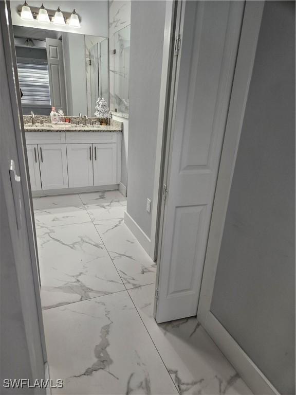 bathroom with marble finish floor, vanity, and baseboards