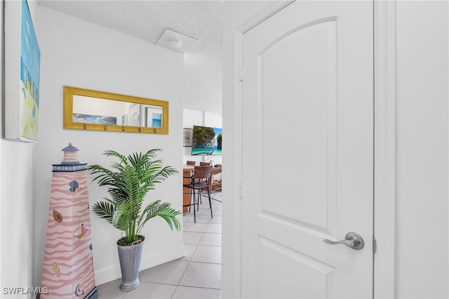 corridor with a textured ceiling and light tile patterned flooring