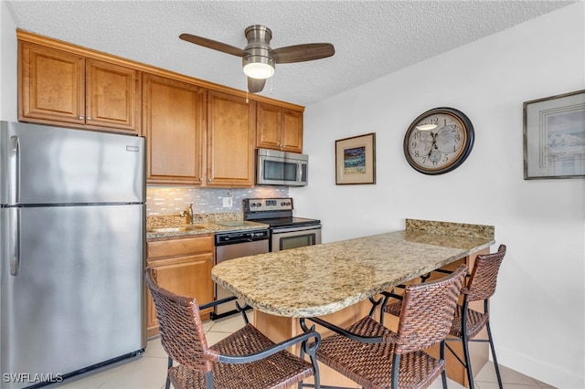 kitchen featuring light tile patterned floors, a textured ceiling, appliances with stainless steel finishes, and tasteful backsplash