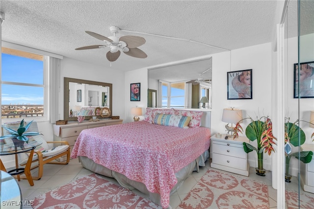 bedroom with ceiling fan, light tile patterned floors, and a textured ceiling