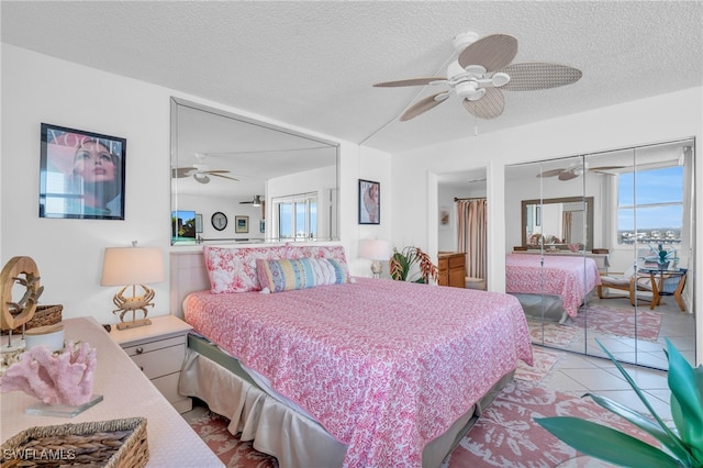 bedroom with ceiling fan, a closet, light tile patterned floors, and a textured ceiling