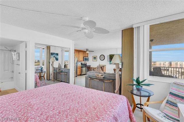 tiled bedroom with ceiling fan, a textured ceiling, stainless steel refrigerator, and ensuite bath