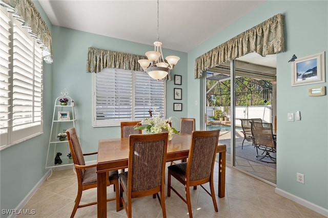 tiled dining room featuring an inviting chandelier and plenty of natural light