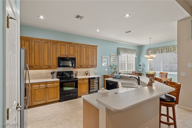 kitchen featuring pendant lighting, black appliances, a kitchen breakfast bar, an island with sink, and beverage cooler