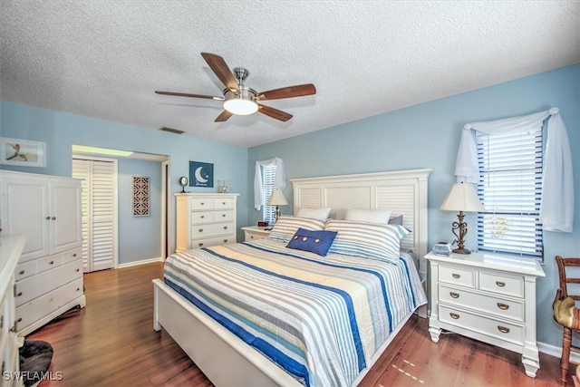 bedroom featuring ceiling fan, dark hardwood / wood-style flooring, and a textured ceiling