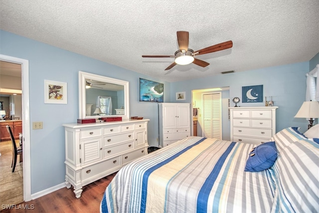 bedroom with a textured ceiling, dark hardwood / wood-style flooring, a closet, and ceiling fan