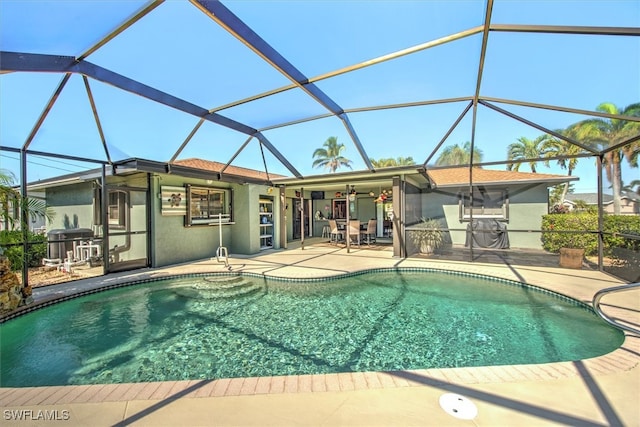 view of swimming pool featuring glass enclosure, ceiling fan, a patio, and grilling area