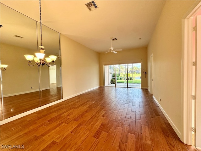 unfurnished room with ceiling fan with notable chandelier and wood-type flooring