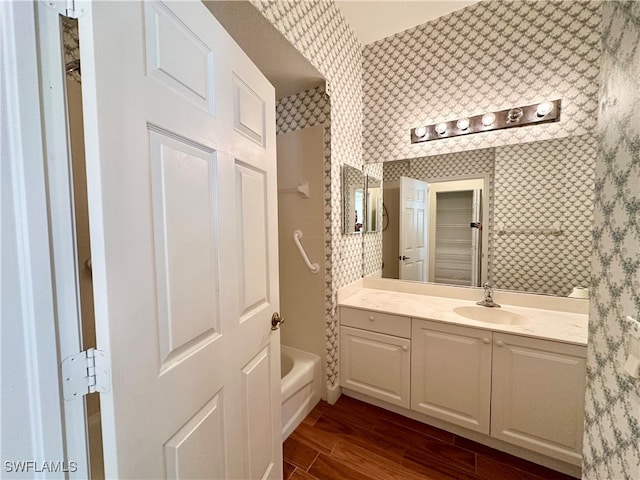 bathroom with a washtub, hardwood / wood-style floors, and vanity