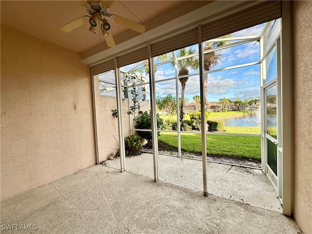 unfurnished sunroom featuring ceiling fan and a water view