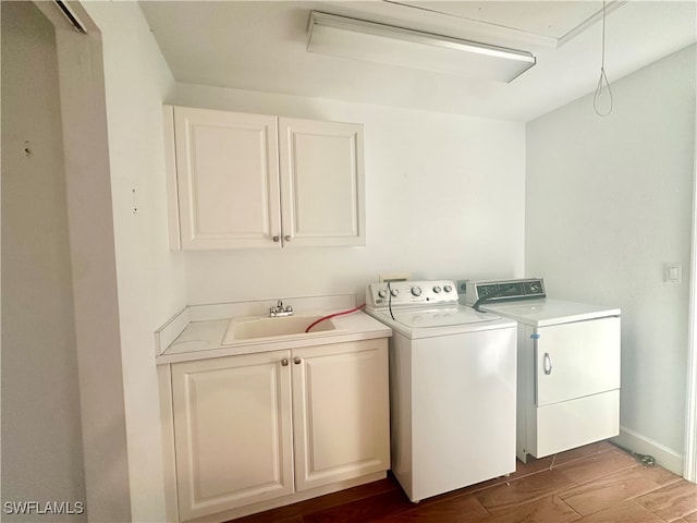 laundry area with cabinets, wood-type flooring, washing machine and dryer, and sink