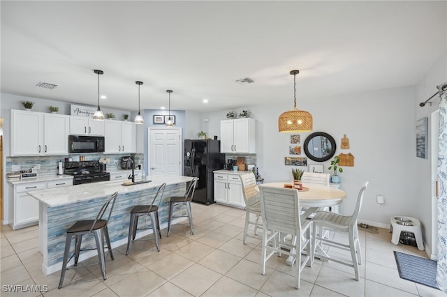 kitchen featuring white cabinetry, decorative backsplash, hanging light fixtures, and black appliances