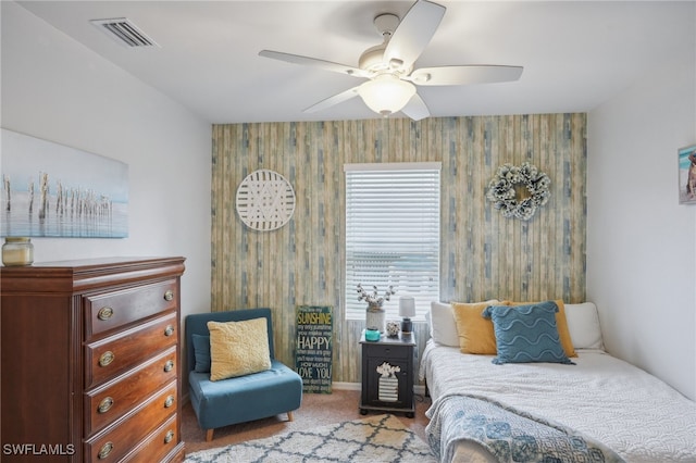 carpeted bedroom with ceiling fan and wood walls