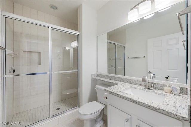 bathroom featuring a shower with door, vanity, and toilet