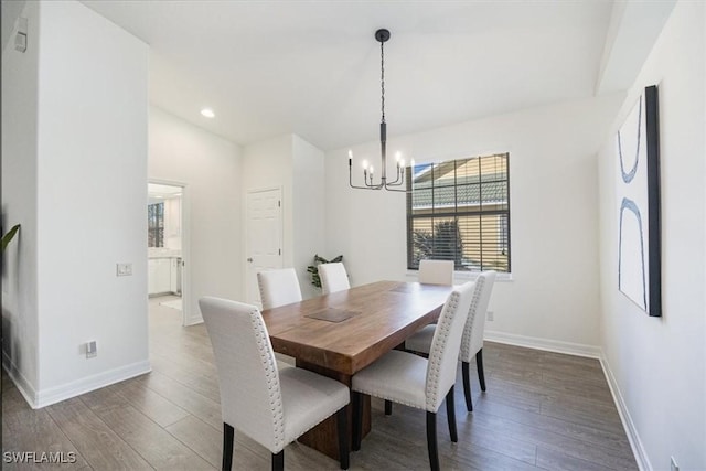 dining area featuring hardwood / wood-style floors, vaulted ceiling, and an inviting chandelier