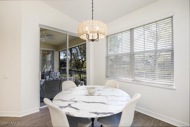 dining room featuring ceiling fan with notable chandelier, dark wood-type flooring, and vaulted ceiling