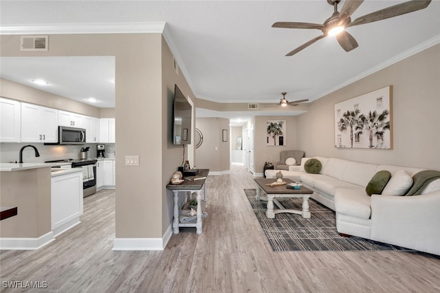 living room featuring ceiling fan, ornamental molding, and light hardwood / wood-style floors