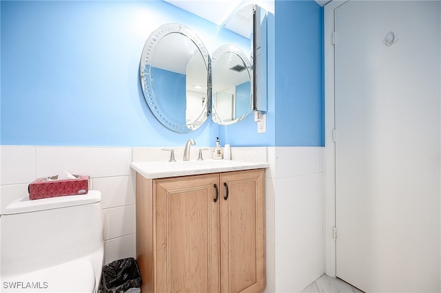 bathroom with vanity, tile walls, and toilet