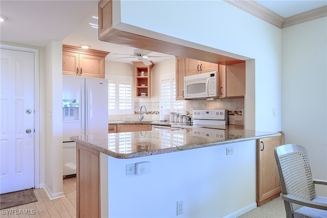 kitchen with sink, white appliances, kitchen peninsula, and dark stone counters