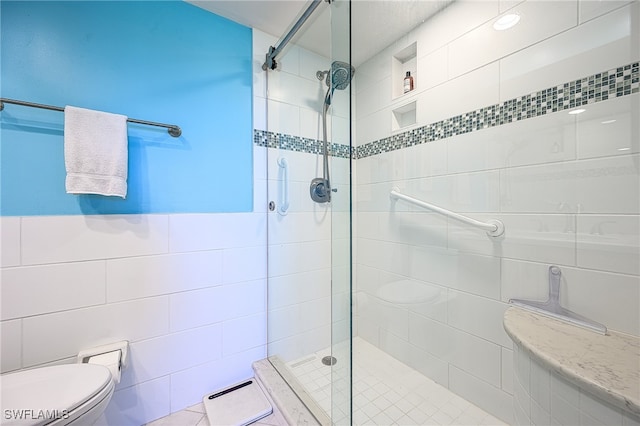 bathroom featuring a tile shower, tile walls, and toilet