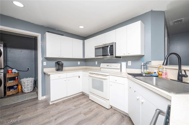 kitchen with light hardwood / wood-style flooring, white cabinetry, stacked washer / drying machine, and electric stove