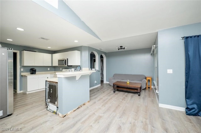 kitchen featuring a kitchen bar, white cabinets, light wood-type flooring, and appliances with stainless steel finishes