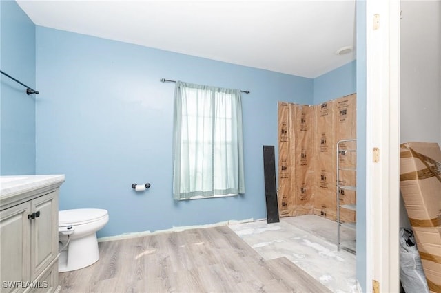 bathroom with hardwood / wood-style floors, vanity, toilet, and walk in shower