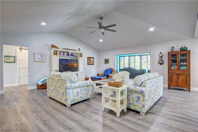 living room featuring ceiling fan, lofted ceiling, and light wood-type flooring