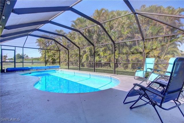 view of swimming pool with glass enclosure and a patio area