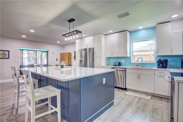 kitchen with decorative light fixtures, a center island, sink, and appliances with stainless steel finishes