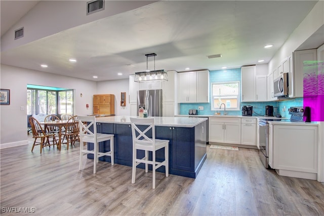 kitchen featuring appliances with stainless steel finishes, pendant lighting, a kitchen island, and a healthy amount of sunlight