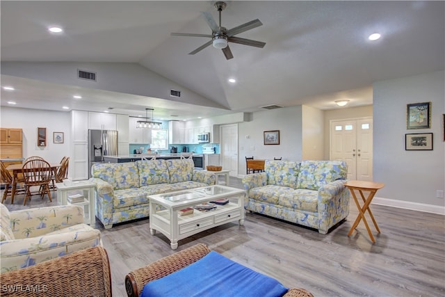 living room featuring ceiling fan, light hardwood / wood-style floors, and vaulted ceiling