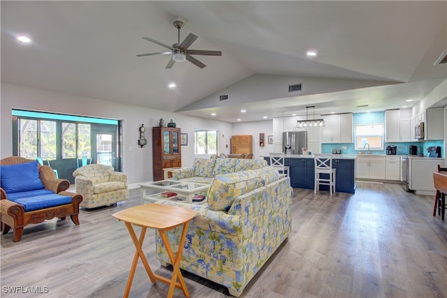 living room with light wood-type flooring, ceiling fan, and lofted ceiling