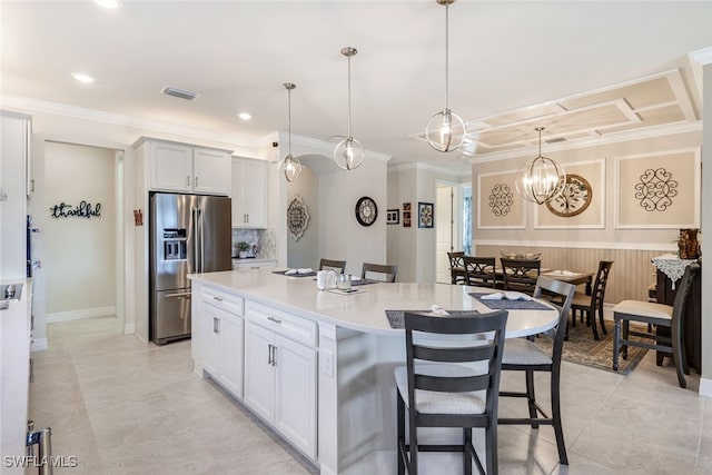 kitchen featuring white cabinetry, stainless steel fridge with ice dispenser, a kitchen island, and decorative light fixtures